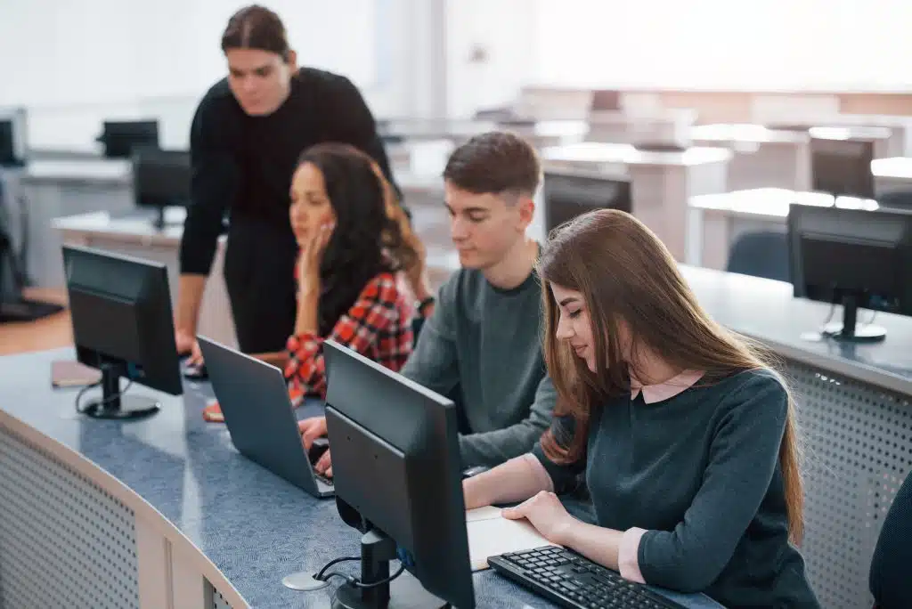 A diverse group of students diligently working on computers in a classroom setting.